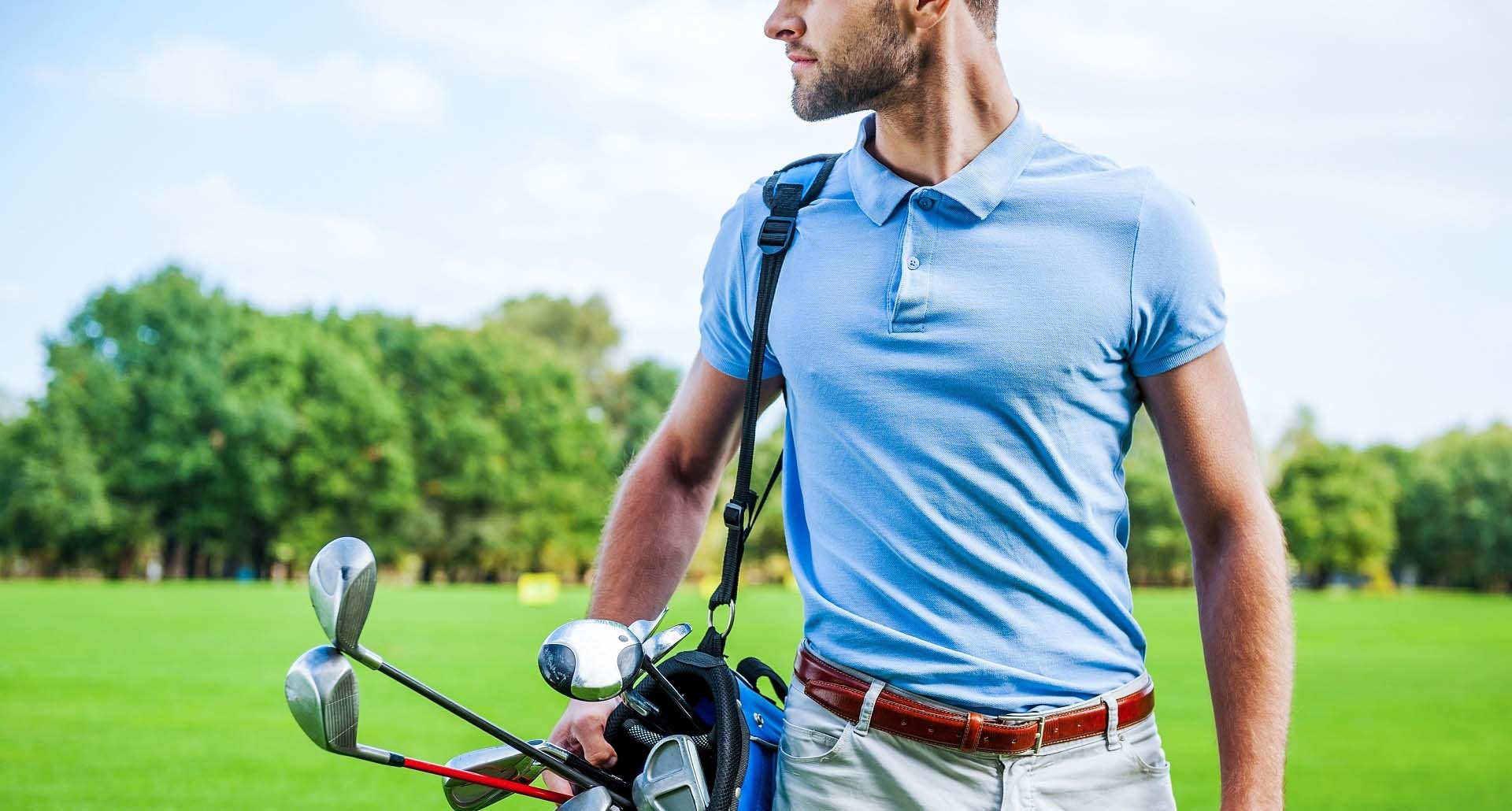 Golf is a style of living. Cropped image of male golfer carrying golf bag with drivers while walking by green grass
